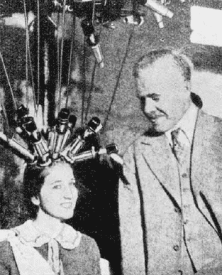 Wie ein Igel: Karl Nessler mit Miss Amerika 1926, der er Dauerwellen-Wickel ins Haar geflochten hat